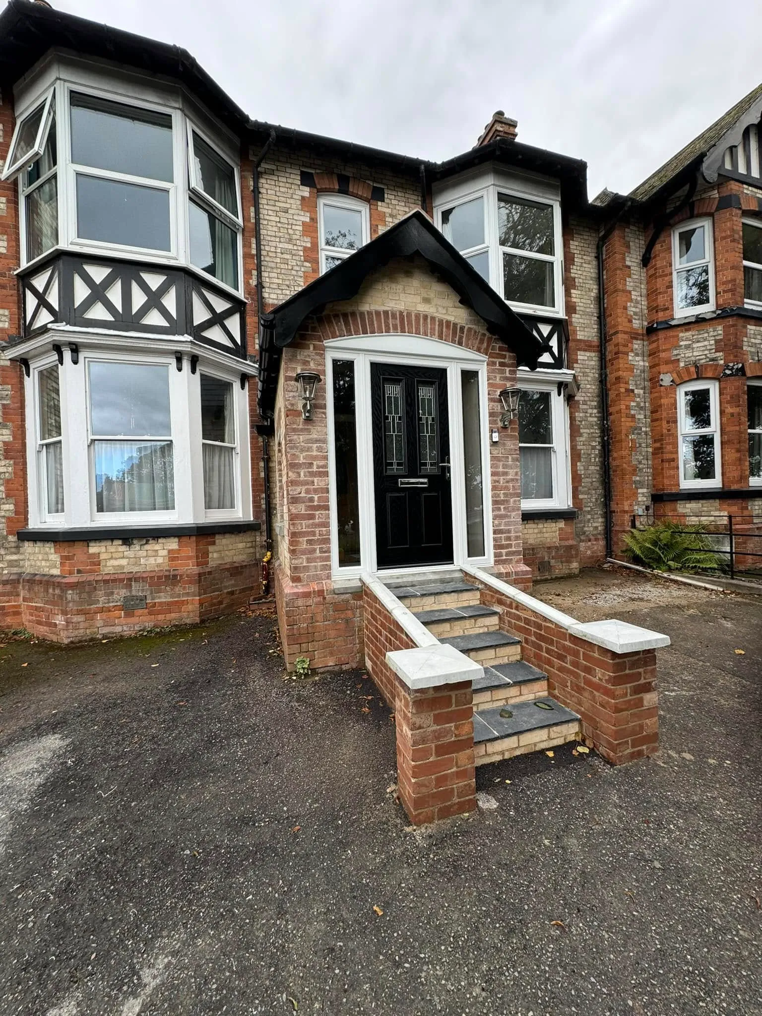 A brick house with white windows and a black door.