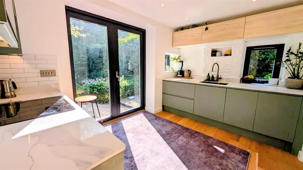 A kitchen with a large glass door leading to the outside.