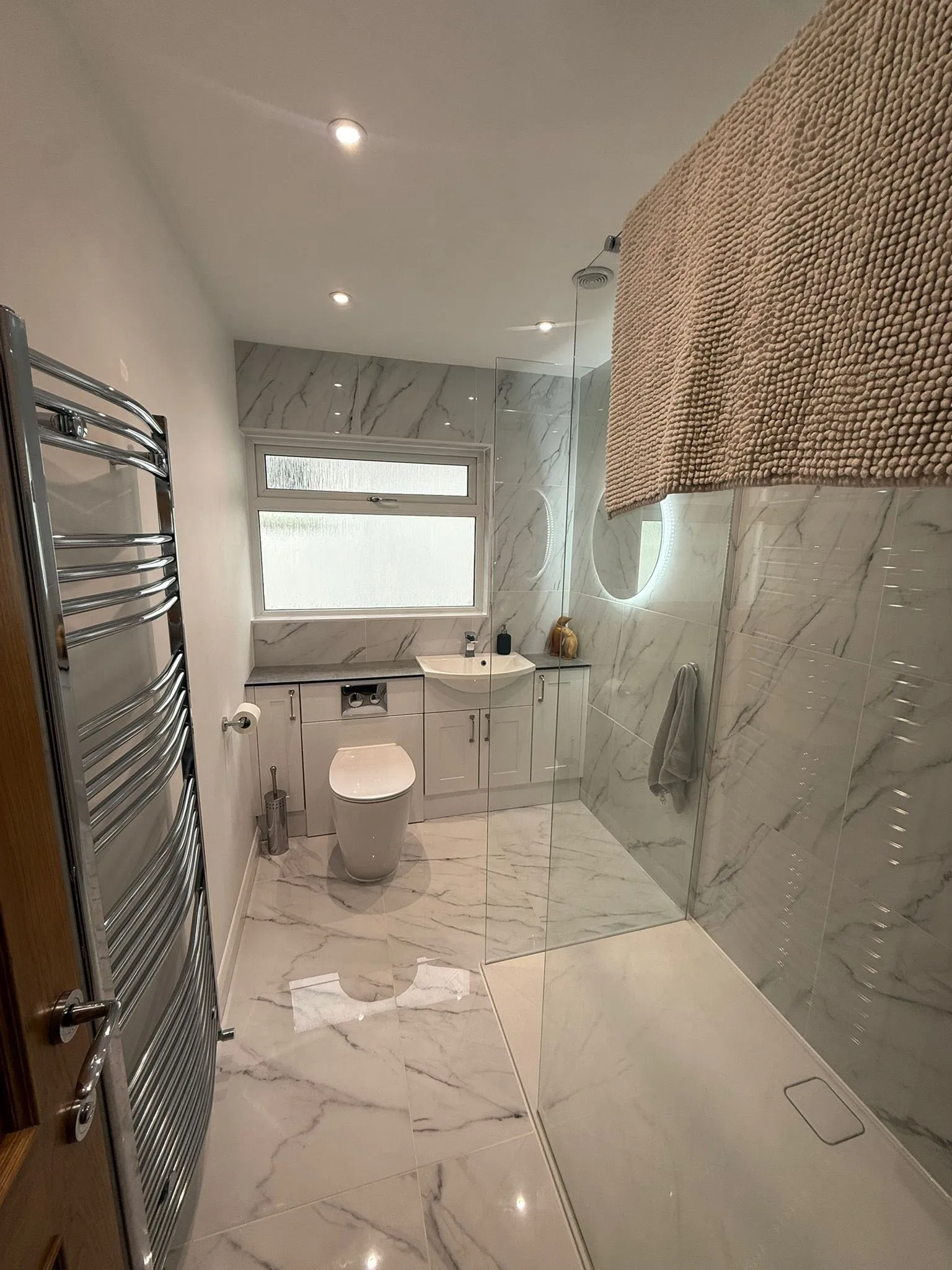 A bathroom with a glass shower door and a toilet.