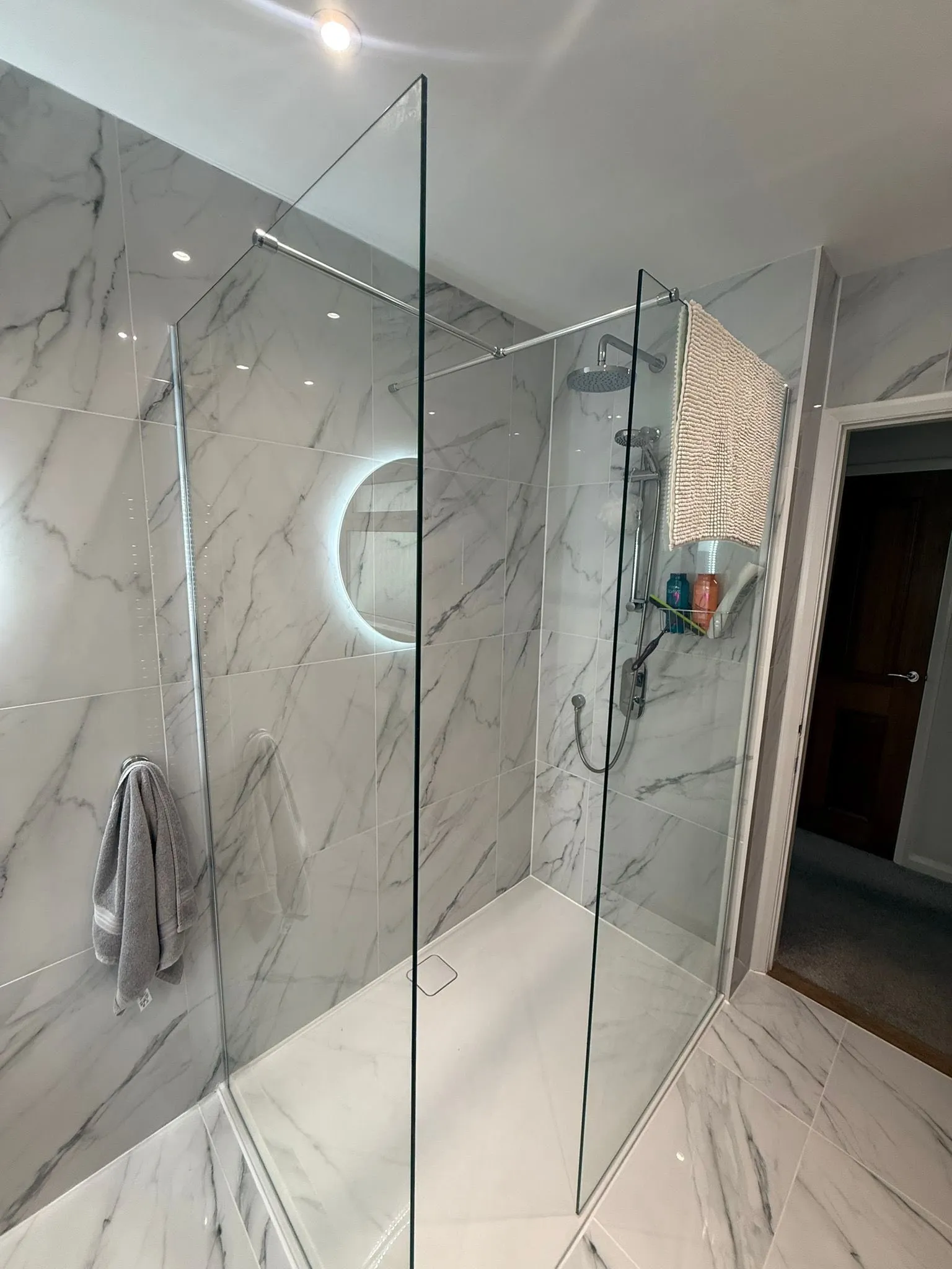 A walk in shower sitting next to a white tiled wall.