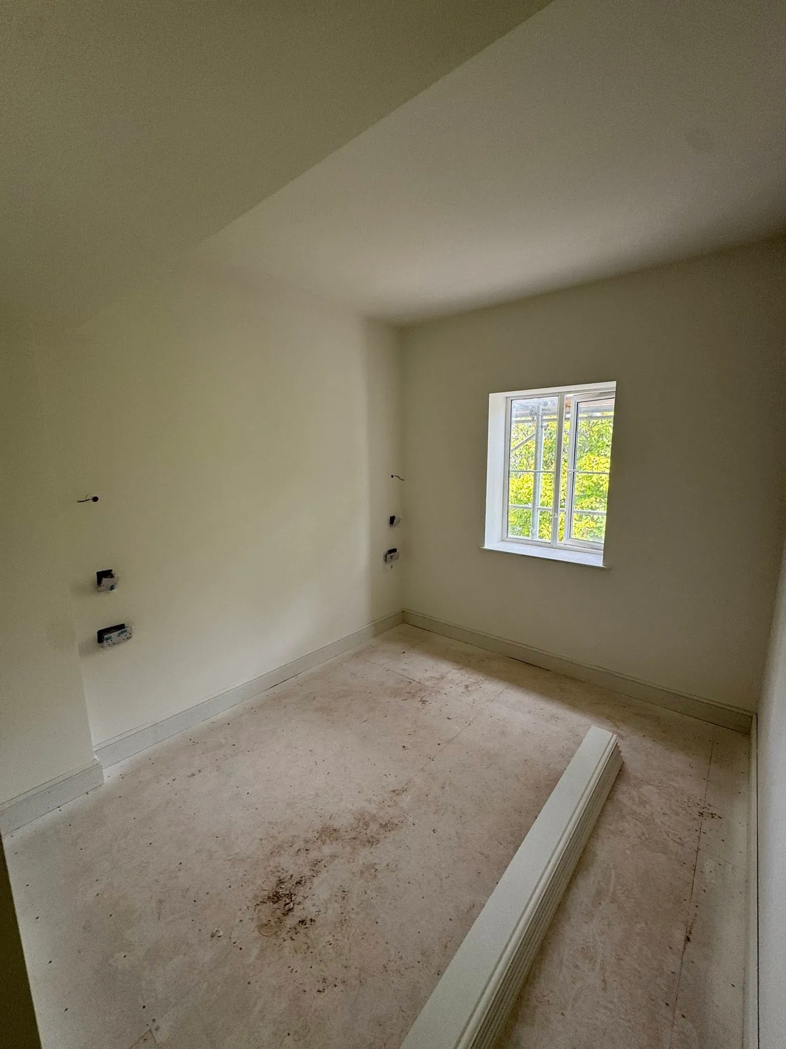 An empty room with a window and no curtains.